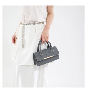 Close-up of gray textured fabric handbag with elegant golden metal clasp detail