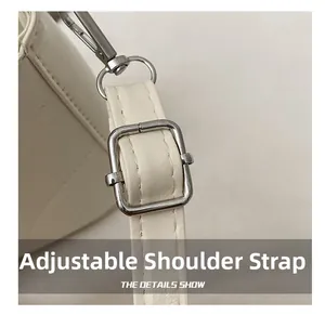 Macro view of white leather shoulder strap with adjustable silver metal buckle and stitching
