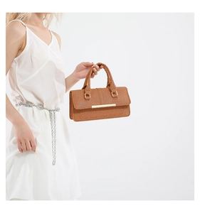 Detail of brown textured tote bag with golden metal bar decoration and thick handles