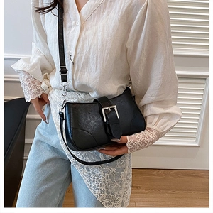 Detail of black textured leather bag with silver buckle and adjustable shoulder strap
