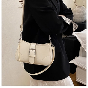 Close-up of beige leather baguette bag on model showing size and side profile view
