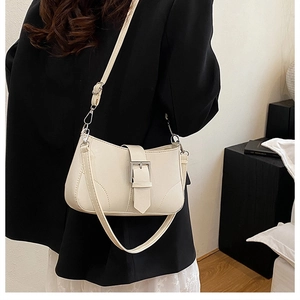 Detail of minimalist beige underarm bag with belt buckle and adjustable shoulder strap