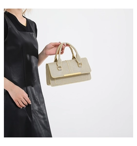 Detail of a woven texture beige handbag featuring gold metal clasp and double handles