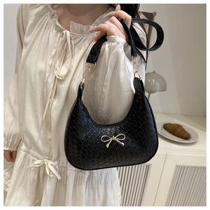 Détail du sac noir à texture tressée avec un fermoir nœud en métal doré