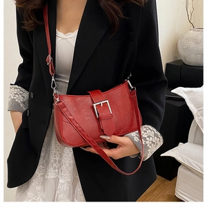 Detail of red shoulder bag with bold silver metal buckle and adjustable leather strap