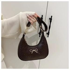 Détail de la texture tressée et du pendentif nœud doré sur le sac demi-lune