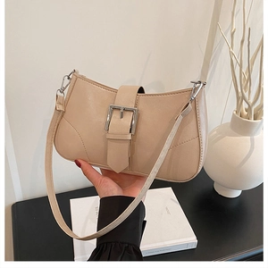 Detail of beige textured leather shoulder bag with silver square metal buckle and strap