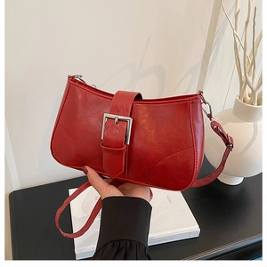 Close-up of red retro underarm bag with silver square buckle held in a modern setting