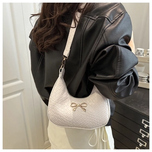 Close-up of woven hobo bag featuring a decorative gold bow buckle and shoulder strap