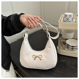 Détail du sac hobo blanc texturé avec un nœud métallique doré et motif peau de serpent