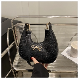 Détail de la texture tressée sur le sac bandoulière croissant avec nœud doré