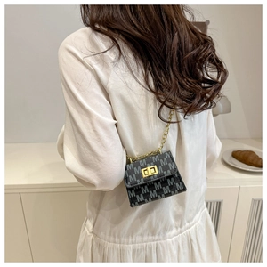 Rear view of a model wearing the mini black chain bag with golden metal hardware