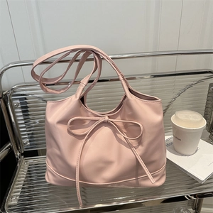 Pink minimalist crossbody bag with bow detail on a stylish modern lounge chair