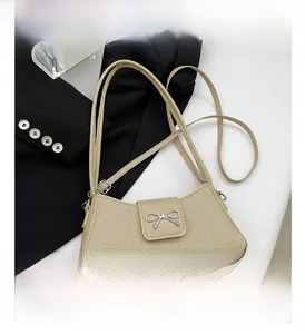 Close-up of beige twill crossbody bag with silver bow buckle on white marble