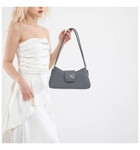 Close-up of gray woven texture baguette bag featuring a silver metal bow buckle detail