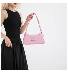 Detail of a pink baguette bag with a silver metal bow buckle and slim shoulder straps