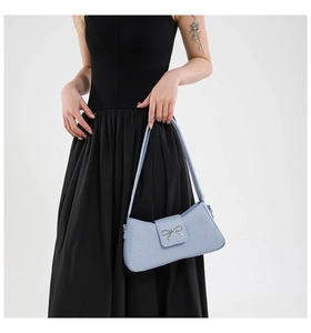 Détail du sac baguette bleu clair avec boucle nœud argenté et texture tissée