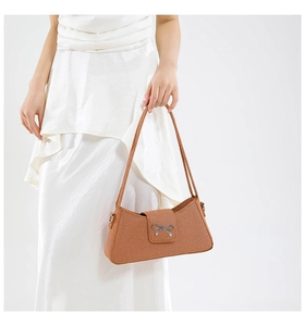 Détail d'un sac en tissu marron texturé avec boucle en métal argenté en forme de nœud