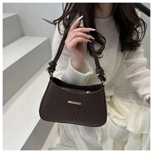 Close-up of brown textured shoulder bag with knotted strap and gold hardware accents