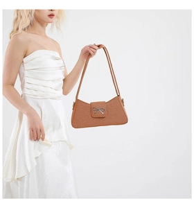 Vue détaillée du sac baguette marron tressé avec une boucle en forme de nœud argenté