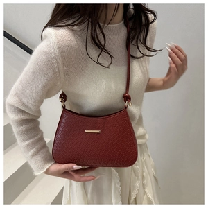Détail du sac à bandoulière rouge foncé en similicuir crocodile avec barre dorée