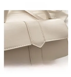Detail of arrow-shaped buckle and precise stitching on off-white crossbody bag