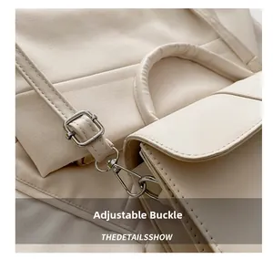 Detail showing adjustable metal buckle and detachable strap hook on cream leather bag