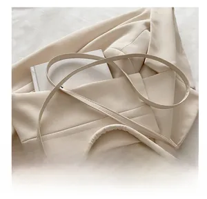 Detailed view of beige faux leather shoulder bag with adjustable strap on beige suit