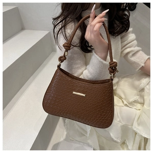 Detail of dark brown crocodile embossed shoulder bag with gold metal trim and knotted strap