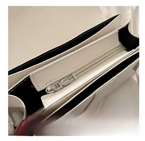 Detail shot of smooth interior metal zipper pocket and lining of the beige square bag