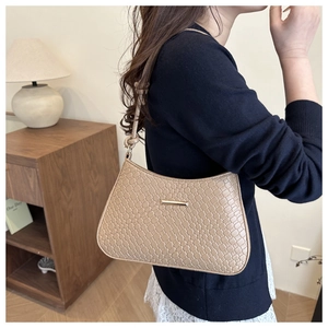 Detail of light brown woven pattern shoulder bag with elegant gold metal fastener