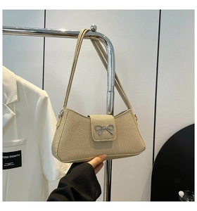 Close-up of beige woven baguette bag with a silver bow metal buckle and slim straps
