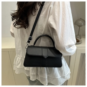 Detailed view of the black matte leather crossbody bag with a curved handle and strap