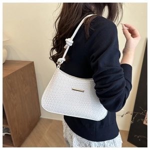 Detailed texture of white woven leather underarm bag with knot strap and gold metal hardware