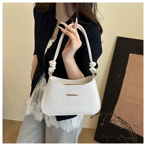 Détail d'un sac à main blanc tressé avec boucle dorée et bandoulière à nœuds élégante