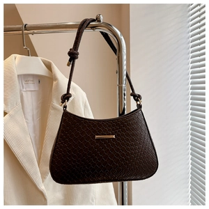 Detail of dark brown woven texture underarm bag with gold metal trim and knotted strap