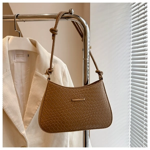 Detail of coffee woven shoulder bag with gold metal trim and knotted strap design