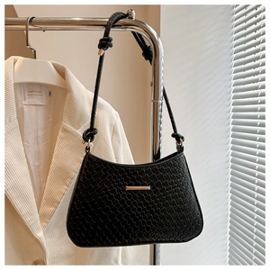 Detail of black woven texture shoulder bag featuring gold hardware and knotted strap
