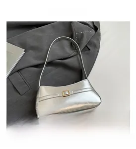 Detail of silver glossy underarm bag with gold buckle on gray suit background