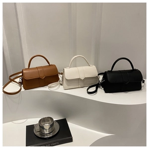 Three minimalist leather crossbody bags in brown, white, and black on display