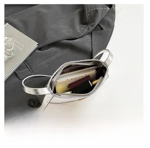 Internal view of silver crossbody bag showing main compartment and zipper pocket storage