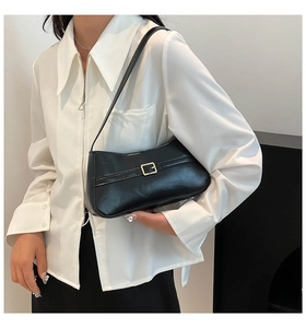 Close-up of a black glossy PU leather baguette underarm bag with a metal buckle