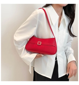 Close-up of a glossy red shoulder bag featuring a modern gold square metal buckle detail