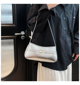 Metallic silver baguette bag with gold metal buckle shown as a stylish underarm shoulder bag