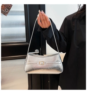 Close-up of a metallic silver shoulder bag featuring a decorative gold square buckle