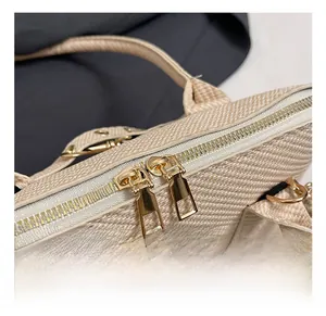 Detailed close-up of premium gold-toned dual zippers and woven texture on a handbag