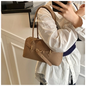 Close-up of textured brown underarm bag with gold metal clasp and double straps