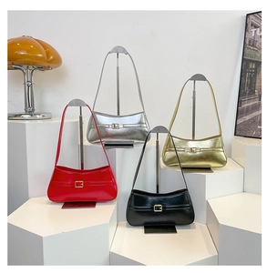 Four colorful baguette shoulder bags in red, silver, gold, and black on display stands