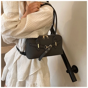 Close-up of black textured pillow bag with gold metal zippers and elegant buckle details