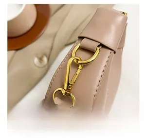 Close-up of shiny gold hardware hook and textured pink leather on the crossbody bag